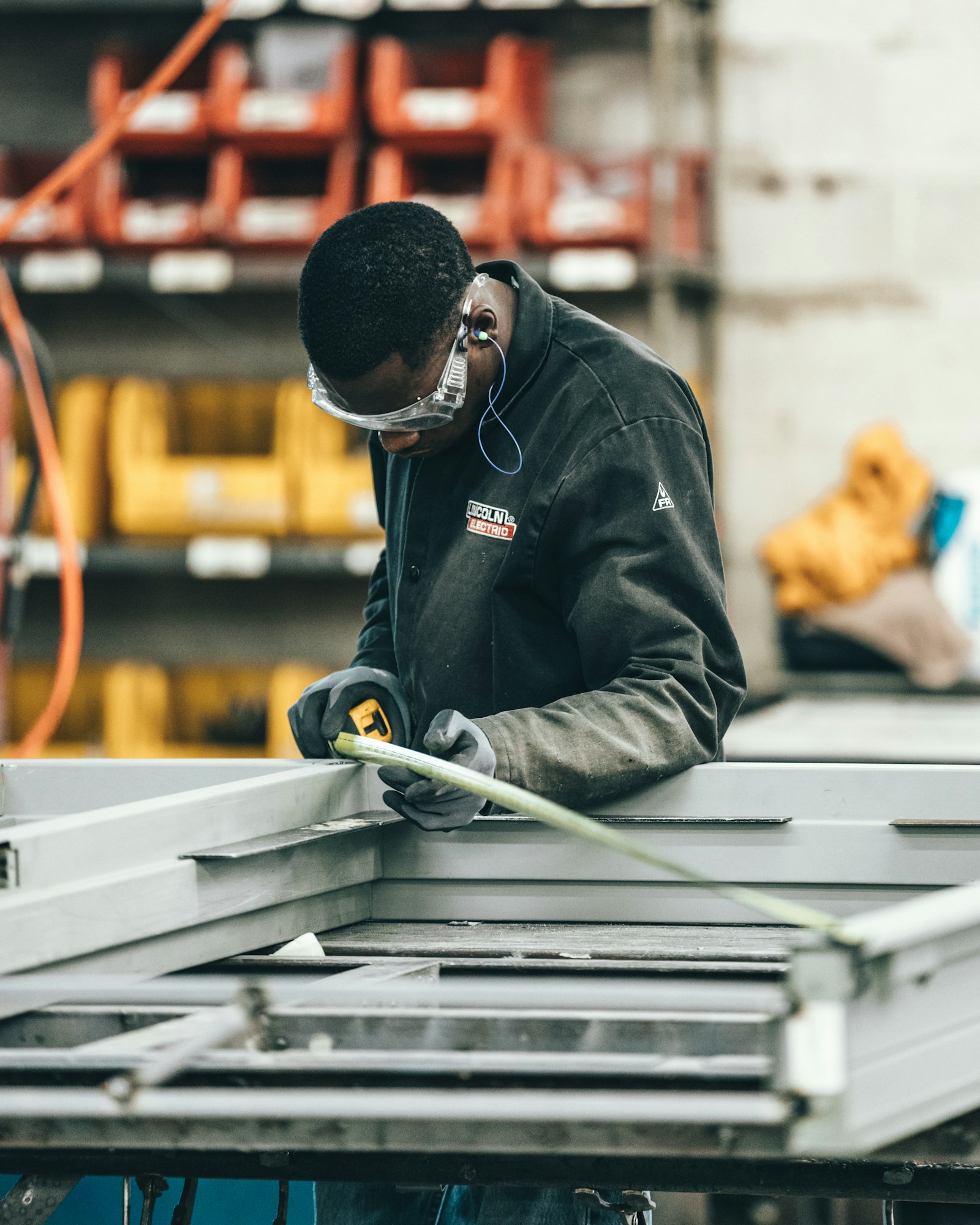 Industrial worker measuring a metal frame in a fabrication workshop
